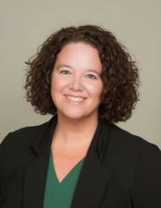 A white female with short brown hair, smiling, wearing a green shirt and a black blazer in a professional headshot.